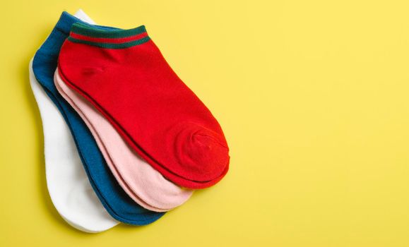 Many socks on a yellow background and space for text. Clothing for autumn and winter. Socks for the cold seasons.