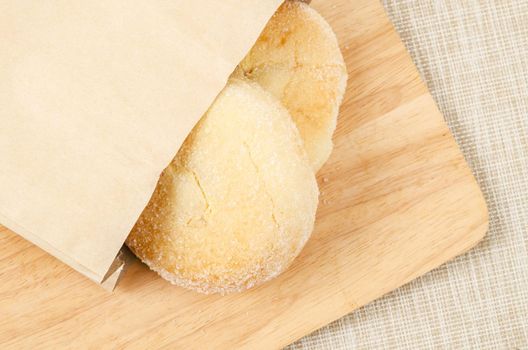 Homemade bread with cream and sugar on top in paper bag.