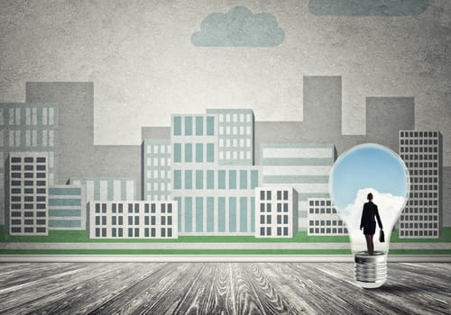 Businesswoman inside light bulb against city drawn concept