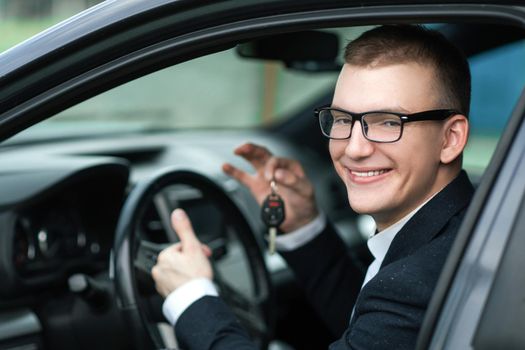 Close up. happy businessman showing the key of his new car