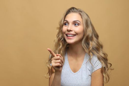 Happy young fashion woman posing for the camera while pointing at you