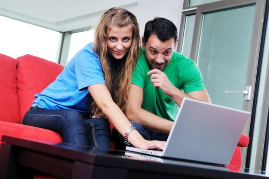 happy young couple have fun and relax at comfort bright apartment and work on laptop computerhappy young couple have fun and relax at comfort bright appartment and work on laptop computer