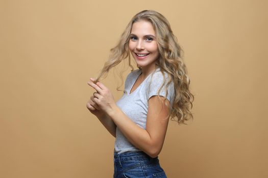 Portrait of young beautiful cheerful girl smiling looking at camera over beige background