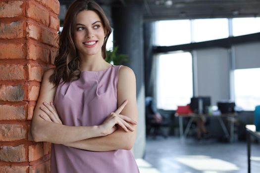 Attractive business woman smiling while standing in the office