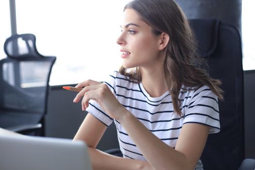 Beautiful business woman in smart casual wear working on laptop in the office.