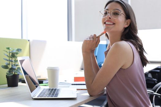 Beautiful business woman in smart casual wear working on laptop in the office.