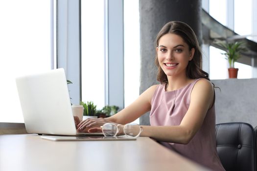 Beautiful smiling business woman is sitting in the office and looking at camera.