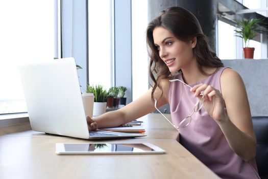 Beautiful business woman in smart casual wear working on laptop in the office.