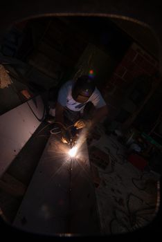 welder with protective mask welding steel structures and bright sparks in construction industry