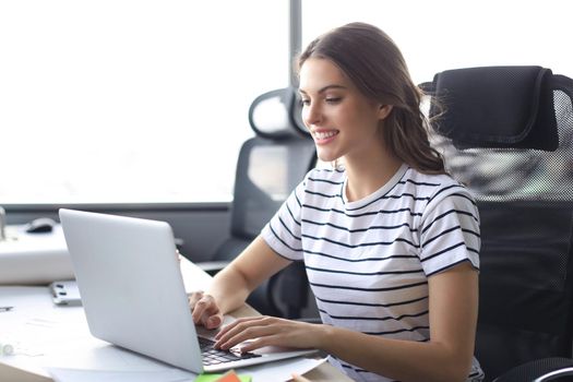Beautiful business woman in smart casual wear working on laptop in the office.