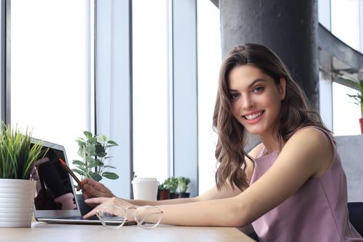 Beautiful smiling business woman is sitting in the office and looking at camera.