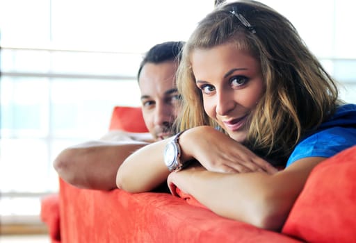 happy couple relaxing on red sofa in big bright new apartment