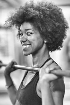 Young Cute african american sport woman in fitness room lifting empty bar