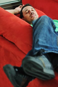 young man relax on red sofa and work on laptop at home indoor 