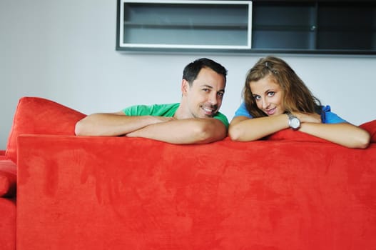 happy couple relaxing on red sofa in big bright new apartment