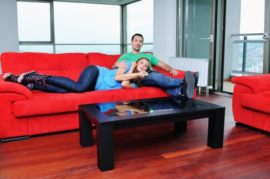 happy couple relaxing on red sofa in big bright new apartment