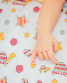 hand of a sleeping newborn baby lying a baby blanket