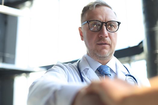 Senior doctor shakes hands with a patient