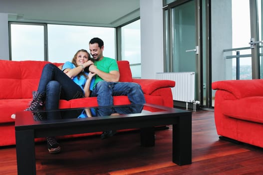 happy couple relaxing on red sofa in big bright new apartment