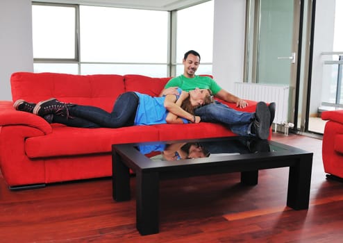 happy couple relaxing on red sofa in big bright new apartment