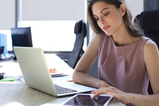 Beautiful business woman in smart casual wear working on laptop in the office.