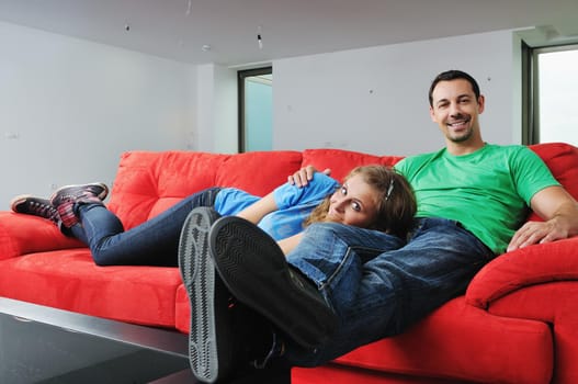 happy couple relaxing on red sofa in big bright new apartment