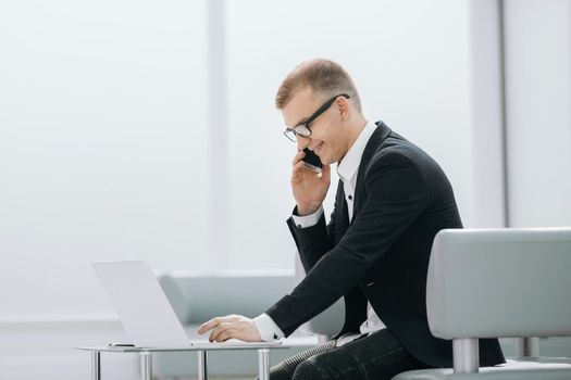 businessman uses gadgets sitting in the office lobby. photo with copy space