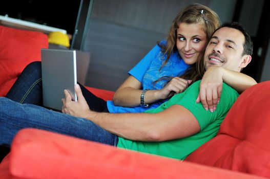 happy young couple have fun and relax at comfort bright apartment and work on laptop computerhappy young couple have fun and relax at comfort bright appartment and work on laptop computer