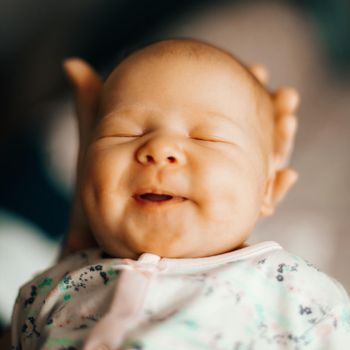 sleeping smiling newborn baby on hands at mum