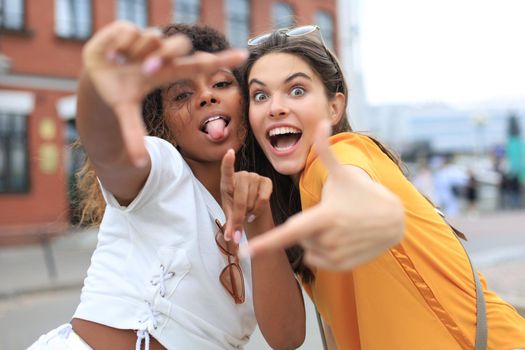 Cute young girls friends having fun together, taking a selfie at the city