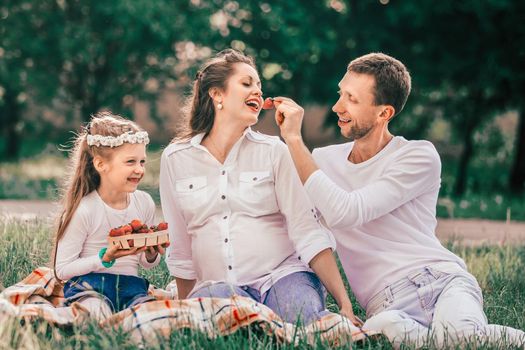 happy family enjoying strawberries at the picnic.good time