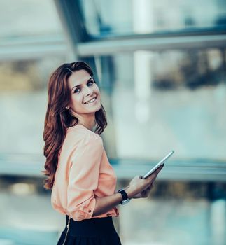 business woman with digital tablet standing near a large window in a modern office.the photo has a empty space for your text