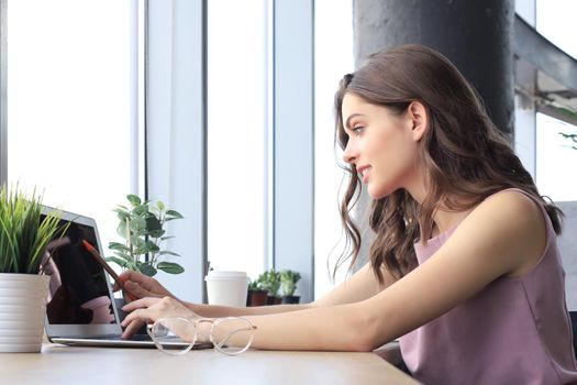 Beautiful business woman in smart casual wear working on laptop in the office.