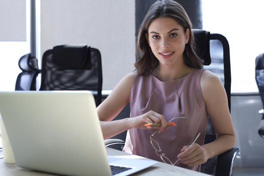 Beautiful business woman in smart casual wear working on laptop in the office.