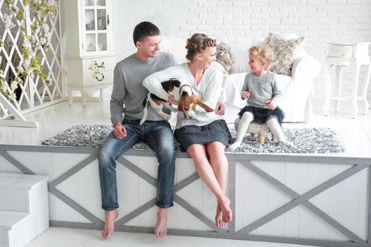 parents and little girl playing with a dog on the bed in the bedroom.
