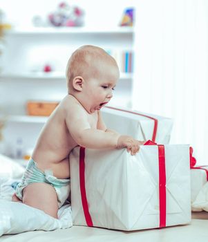 one year old cute baby playing with shopping in boxes on the sofa in the nursery