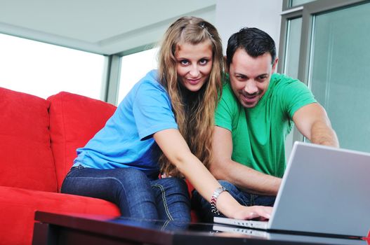 happy young couple have fun and relax at comfort bright apartment and work on laptop computerhappy young couple have fun and relax at comfort bright appartment and work on laptop computer