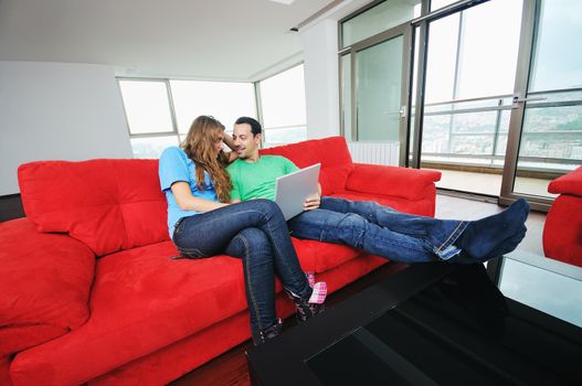 happy young couple have fun and relax at comfort bright appartment and work on laptop computer