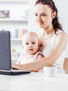 young mother and baby using laptop to communicate with grandma via Skype,at home in the nursery