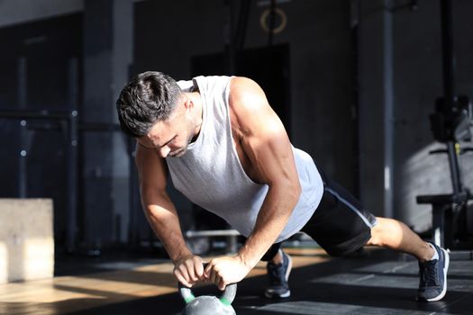 Fit and muscular man focused on lifting a dumbbell during an exercise class in a gym