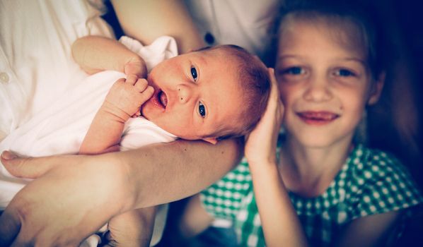 older sister with her newborn sister in the room for children