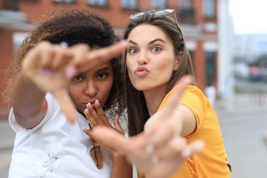 Two laughing friends enjoying weekend together and making selfie on city background