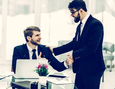 handshake Manager and the client before signing a contract in the workplace in a modern office.the photo has a empty space for your text