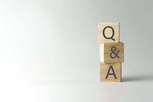 Q and A alphabet on wooden cube in hand hold with background. Question and answer meaning concept.