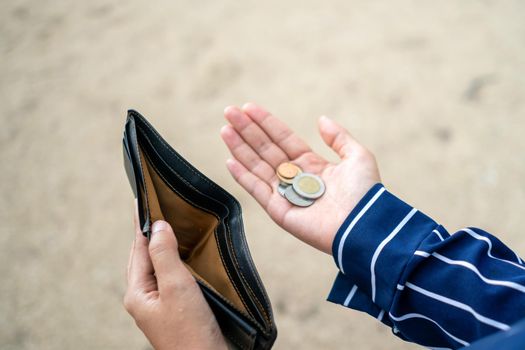 Woman holds an empty purse and coins in hand meaning money financial problem or bankrupt jobless, broke after credit card payday jobless, debt concept.