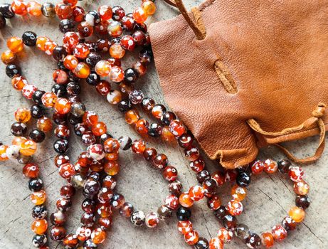 Sunny beads of amber fireplace faceted agate with leather jewelry pouch bag on rustic background