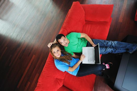 happy young couple have fun and relax at comfort bright apartment and work on laptop computerhappy young couple have fun and relax at comfort bright appartment and work on laptop computer