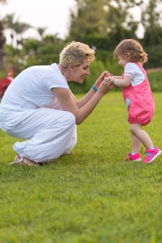 Young Mother and cute little daughter enjoying free time playing outside at backyard on the grass, happy family in nature concept