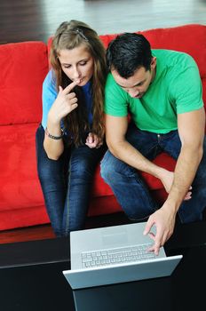 happy young couple have fun and relax at comfort bright apartment and work on laptop computerhappy young couple have fun and relax at comfort bright appartment and work on laptop computer