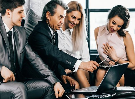 A group of businessmen discussing the policies of the company using a laptop in a modern office